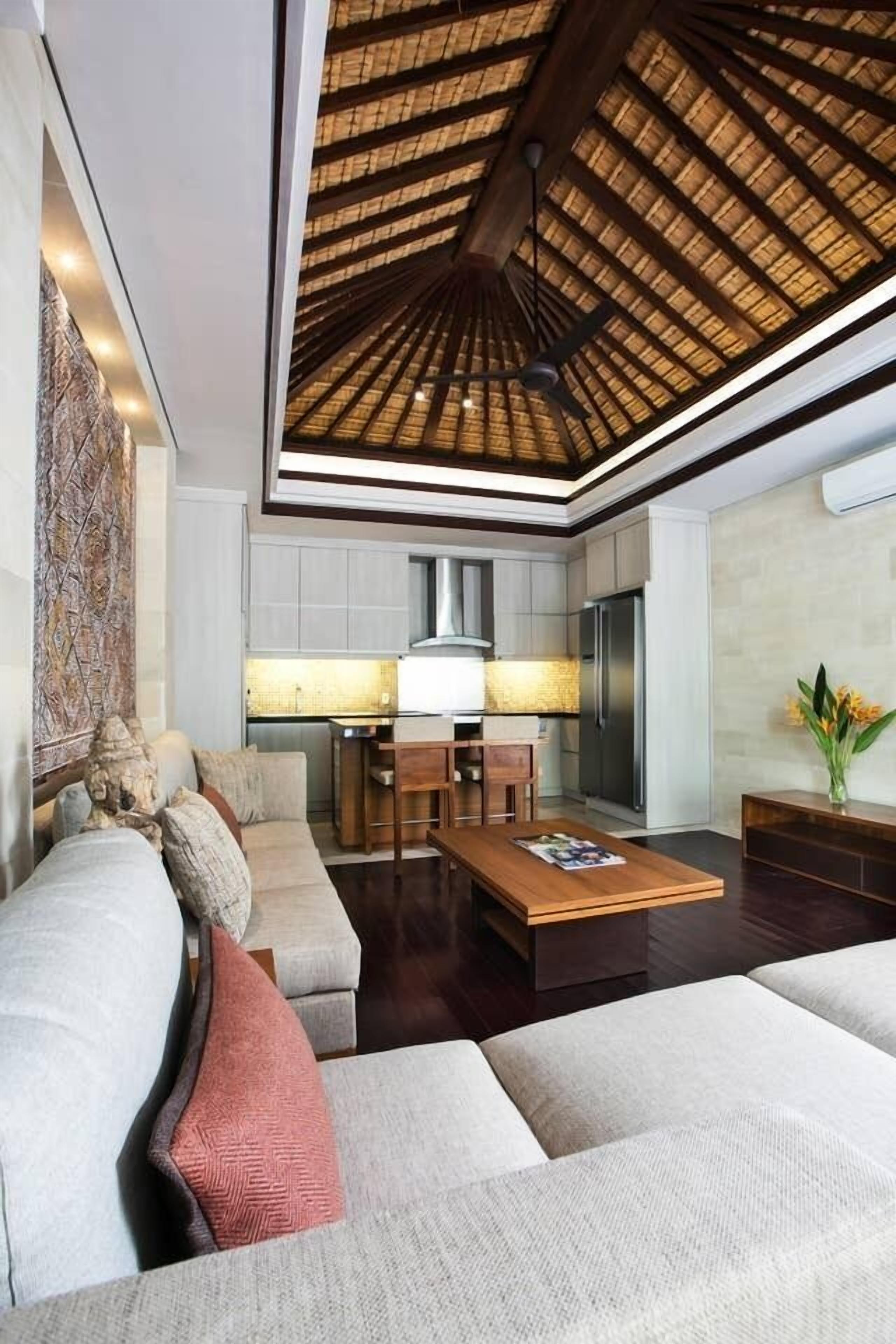 A spacious living area with a high ceiling, a modern kitchen in the background, and a comfortable seating arrangement.