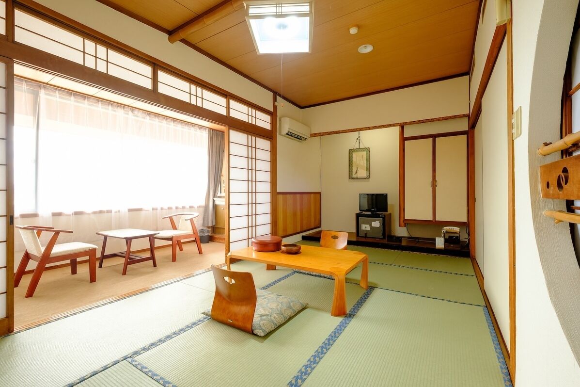 A traditional Japanese room with tatami flooring, a low wooden table, and a sliding door.