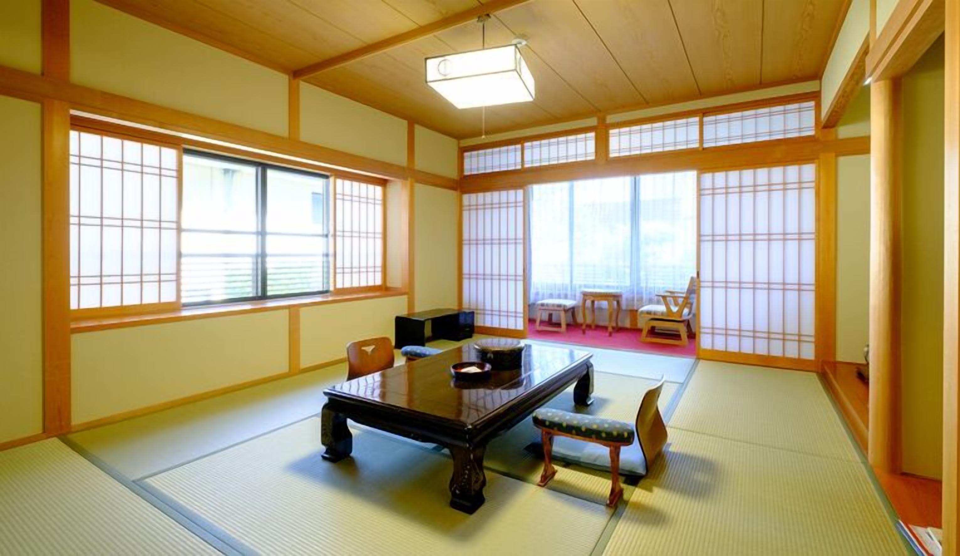 A traditional Japanese room with tatami flooring, a low table, and sliding doors.