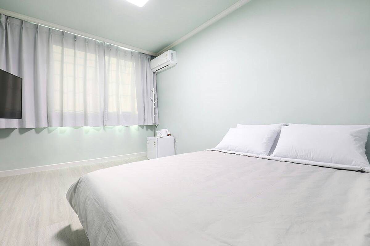 Ein Schlafzimmer mit einem Bett, einem an der Wand montierten Fernseher und einer Klimaanlage.