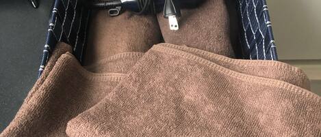 A suitcase with a 'naturam' tag, a brown towel, and a striped cloth on a black surface.