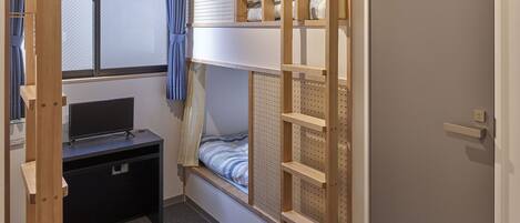 Een slaapkamer met een stapelbed, een bureau en een deur.