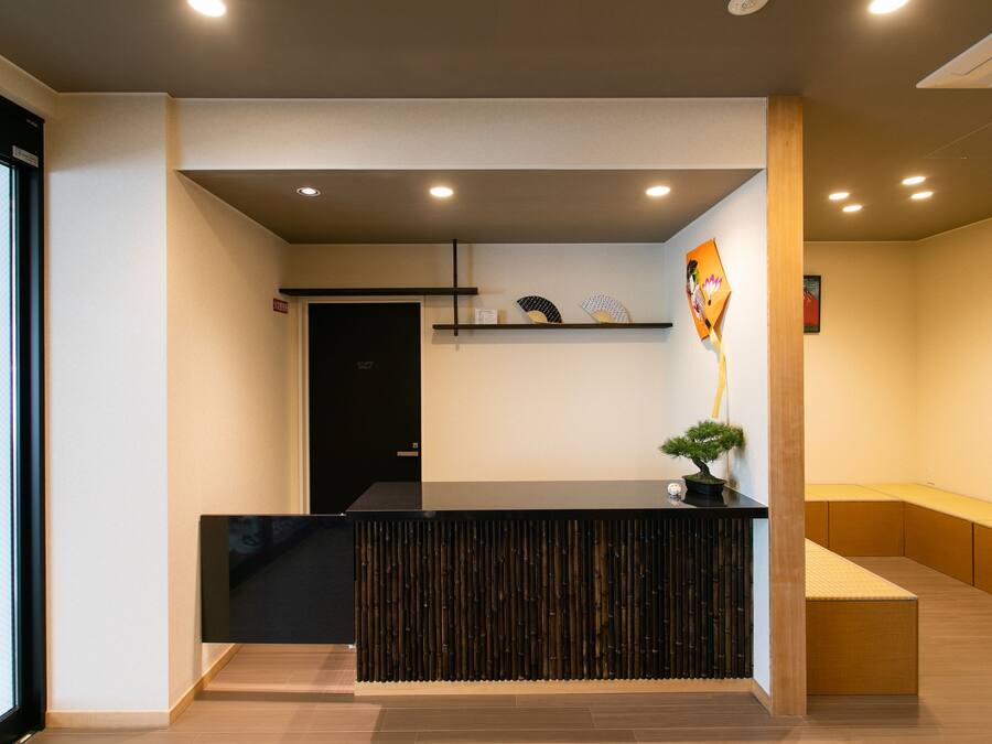 A reception area with a black reception desk, a small potted plant, and a bench.