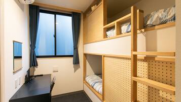 A compact room with bunk beds, a desk, and a window with curtains.