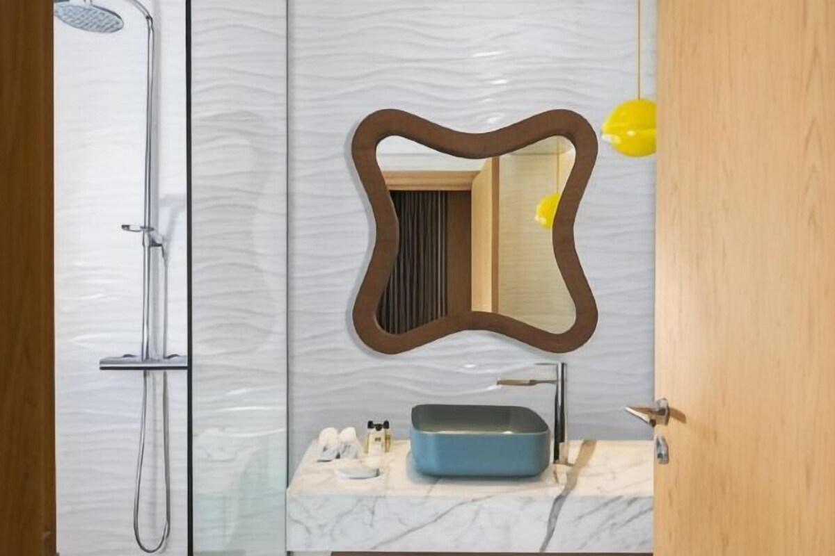 A bathroom with a shower, a mirror, and a sink with toiletries.