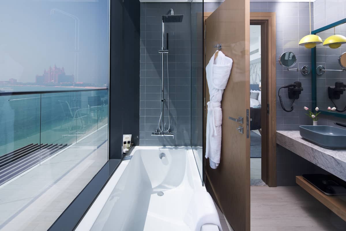Une salle de bain moderne dotée d’une grande baignoire, d’une douche et d’un meuble-lavabo avec un miroir.