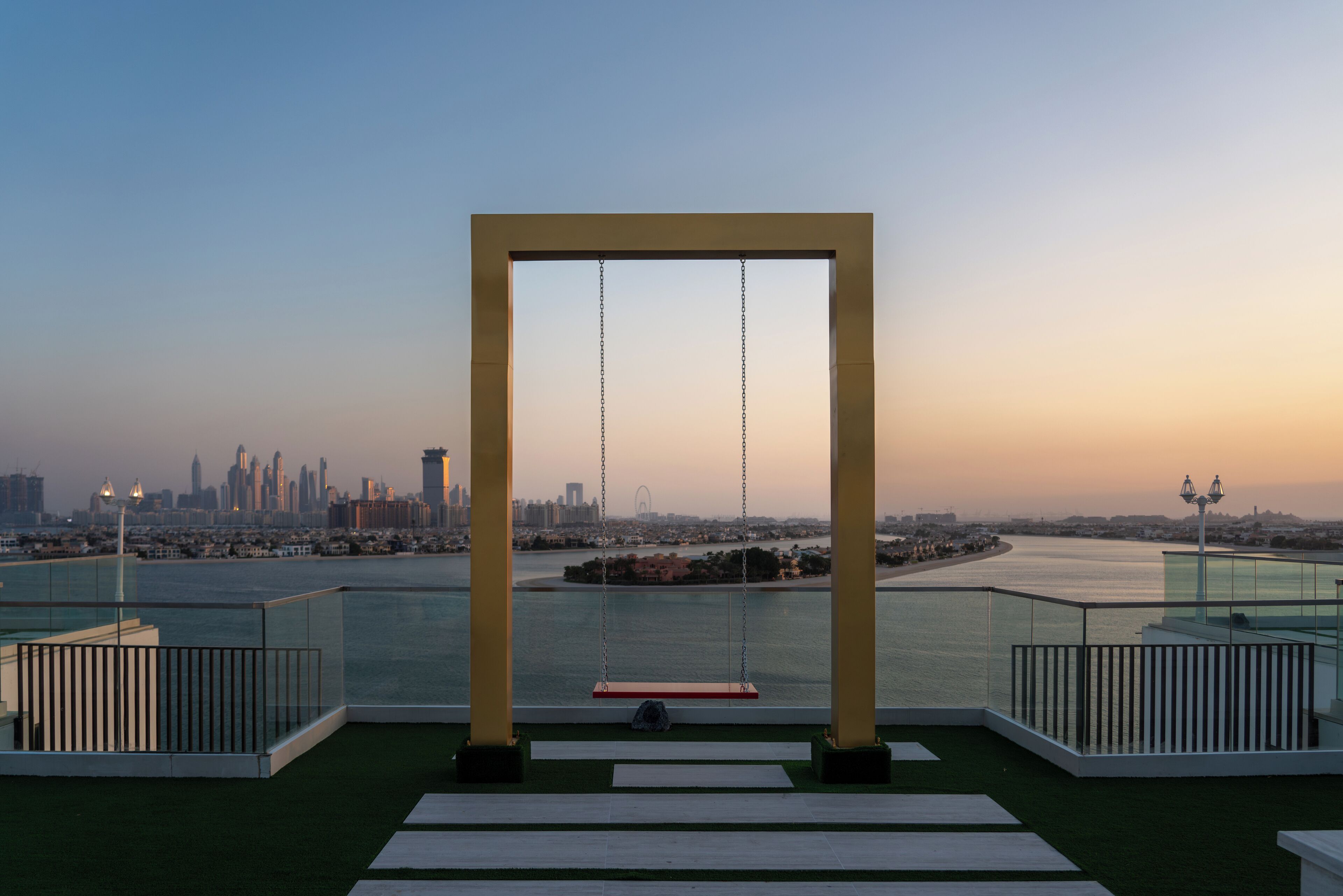 A swing set with a view of a city skyline at sunset.