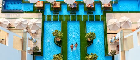 A large swimming pool with multiple lanes, surrounded by lounge chairs and umbrellas.