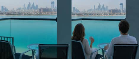 A balcony with a city view, two chairs, and a table.