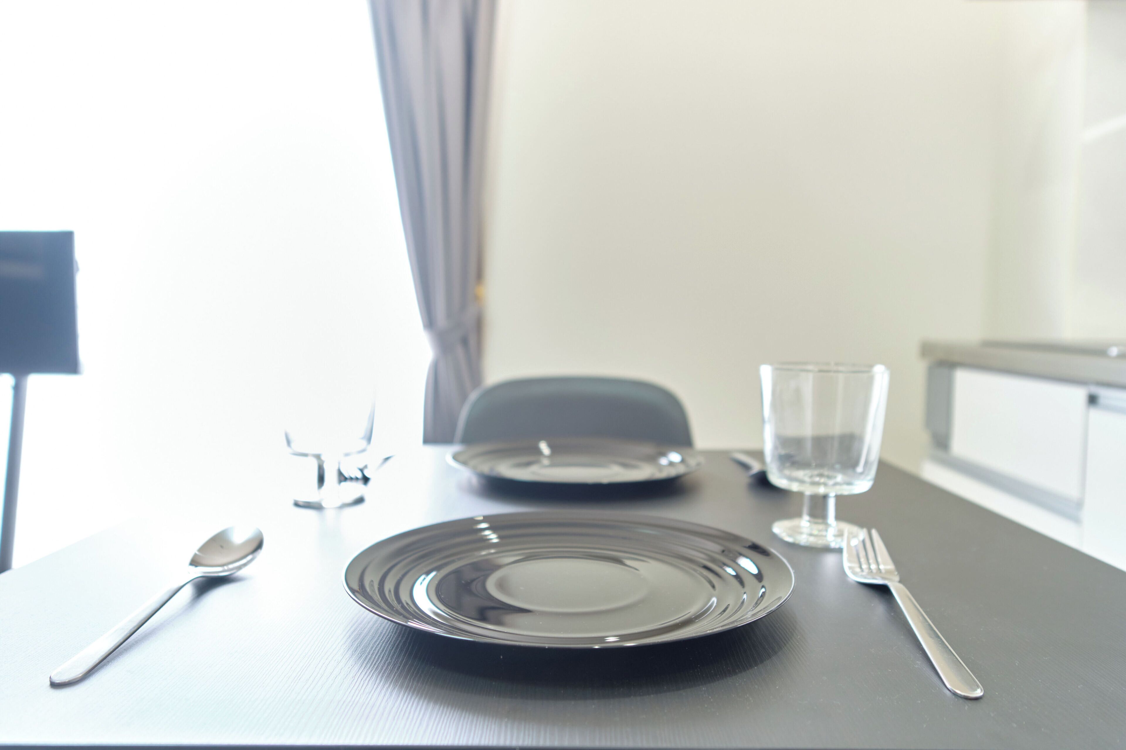 A dining table with a plate, a glass, a spoon, and a fork.