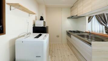 A compact kitchen with a washing machine, a microwave, and a stove.