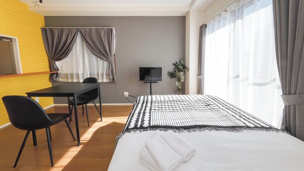 A hotel room with a bed, a desk, a chair, a TV, and a window with curtains. - Shinagawa House -Ryo- (Tokyo)