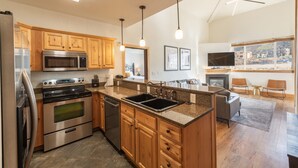 A modern kitchen with wooden cabinets, stainless steel appliances, and a large island with a sink. - Step out the door and on the Canyons Village Skyway Gondola - Pool, Sauna, Steam Room Mountain Views (Park City)