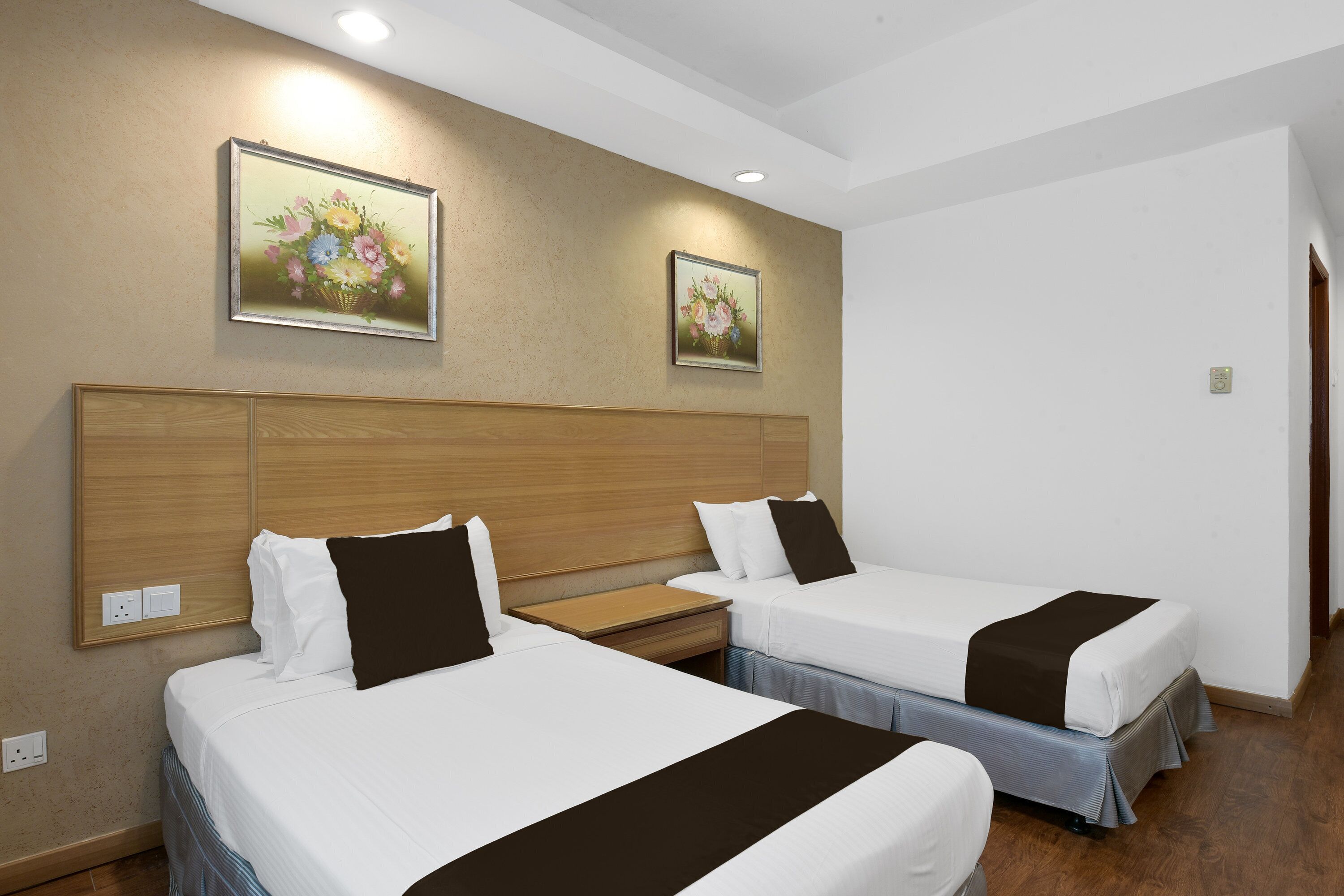 A hotel room with two beds, wooden headboards, and wall-mounted artwork.