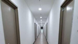Un pasillo largo y estrecho con puertas a ambos lados, que conduce a habitaciones individuales.