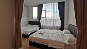 Una habitación de hotel con dos camas, un ventanal con cortinas y vistas a la ciudad.