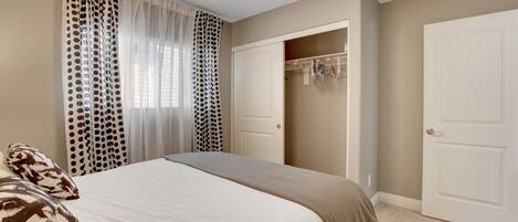 A bedroom with a bed, a closet, and a window with curtains.