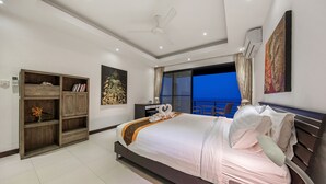 Quarto moderno com cama grande, ventilador de teto, ar condicionado, guarda-roupa e vista para o exterior.