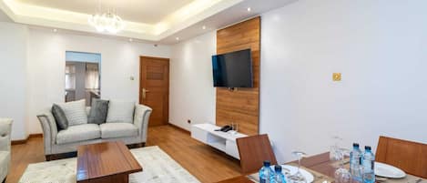A modern living room with a sofa, coffee table, and dining table set for four.