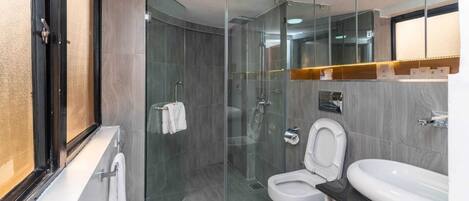 Et moderne badeværelse med brusekabine i glas, toilet og håndvask.