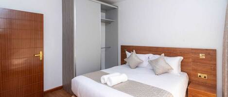 A hotel room with a wooden bed, a wardrobe, and a bathroom door.