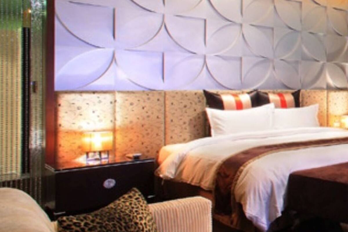 A hotel room with a large bed, a nightstand, and a seating area with a sofa and armchairs.