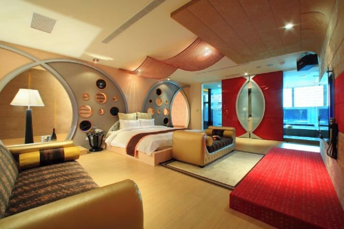 A modern hotel room with a bed, seating area, and a large window offering a view.