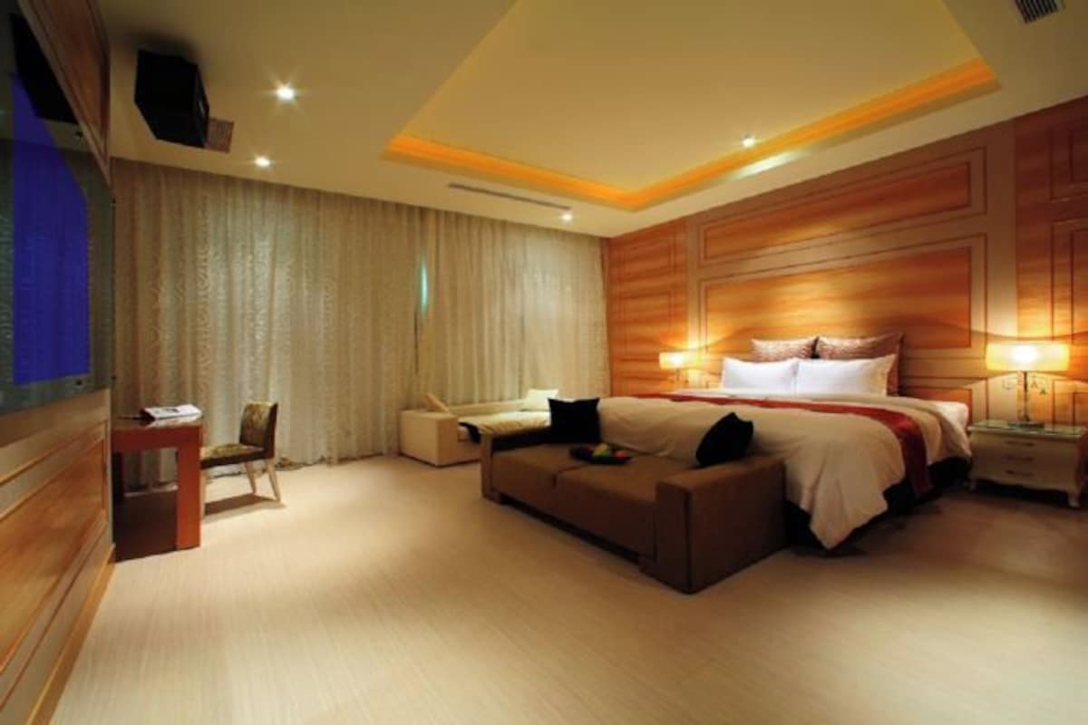 Una habitación de hotel moderna con una cama grande, un sofá, un escritorio y una silla.