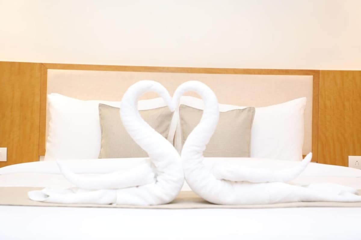 A bed with two white towels arranged in the shape of swans.