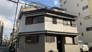 A two-story building with a tiled facade, a small entrance, and a parked van. - Color Namba South 2 (Osaka)