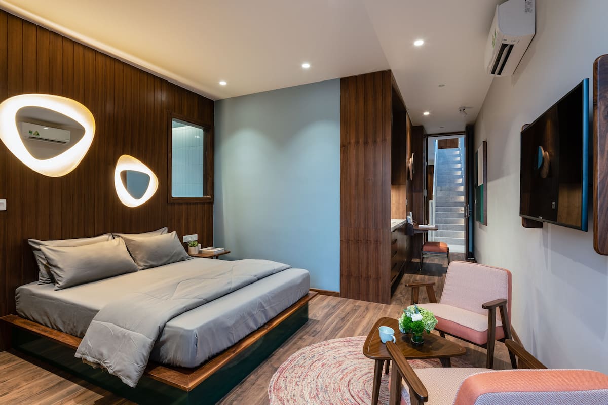 A modern bedroom with a bed, bedside tables, a chair, and a small table with a plant.