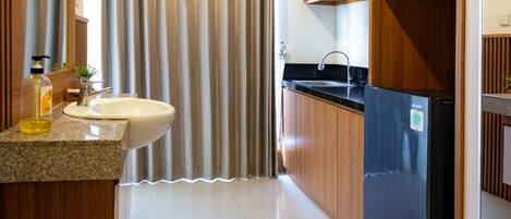 A modern kitchen with a sink, a refrigerator, and wooden cabinets.