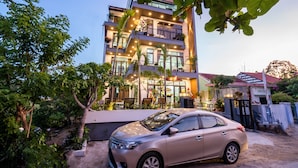 A multi-story building with balconies, a car parked in front, and surrounding greenery. - Ancient River Villa (Da Nang)