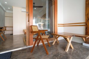 A modern room with a wooden bench, a chair, and a small table. - Sunlit Hostel (General Luna)