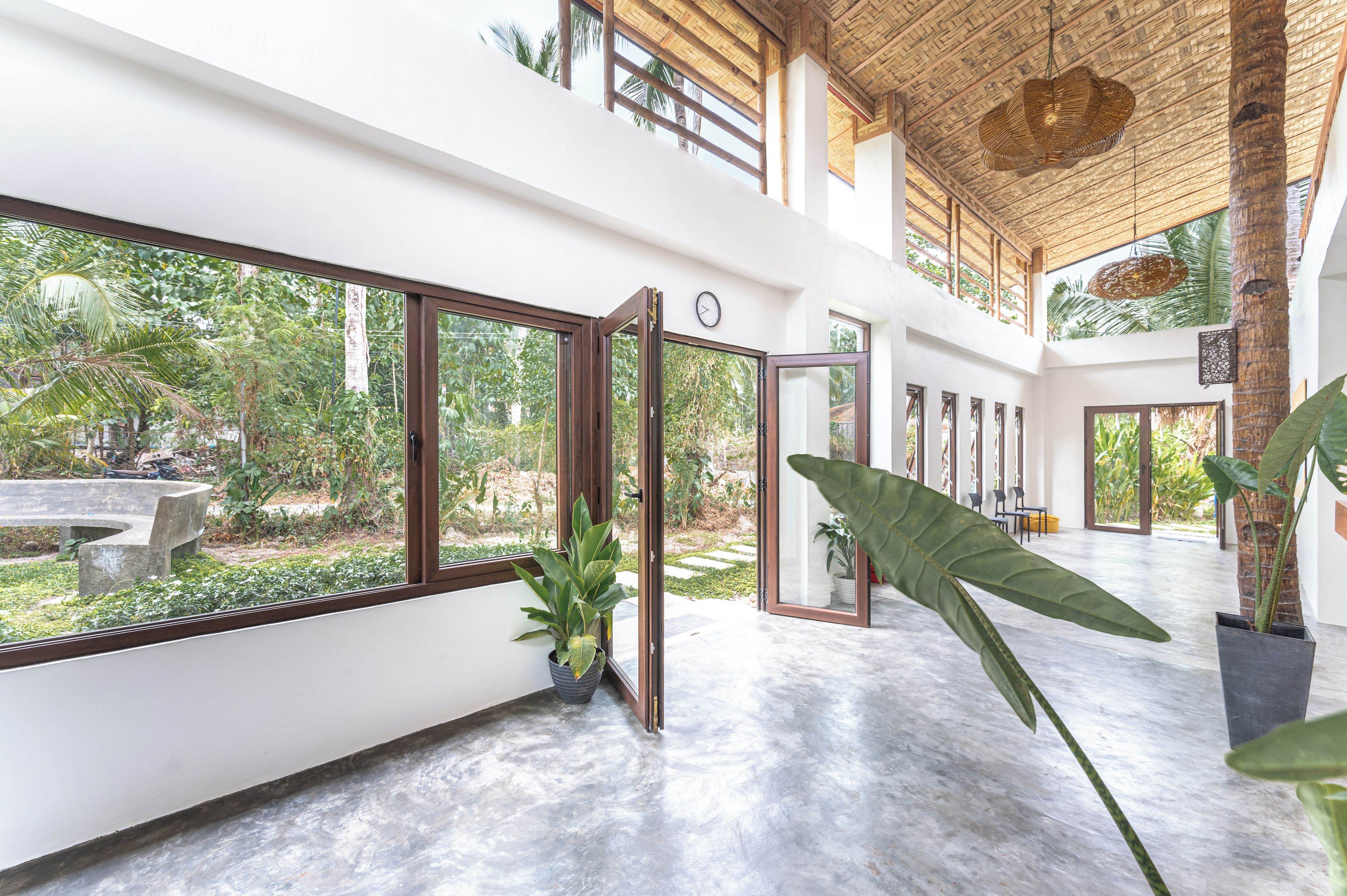 A spacious indoor area with large windows, a ceiling with a woven pattern, and a potted plant.