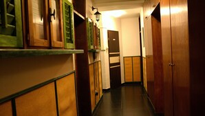 Un couloir étroit avec des portes en bois et des fenêtres à cadre vert.