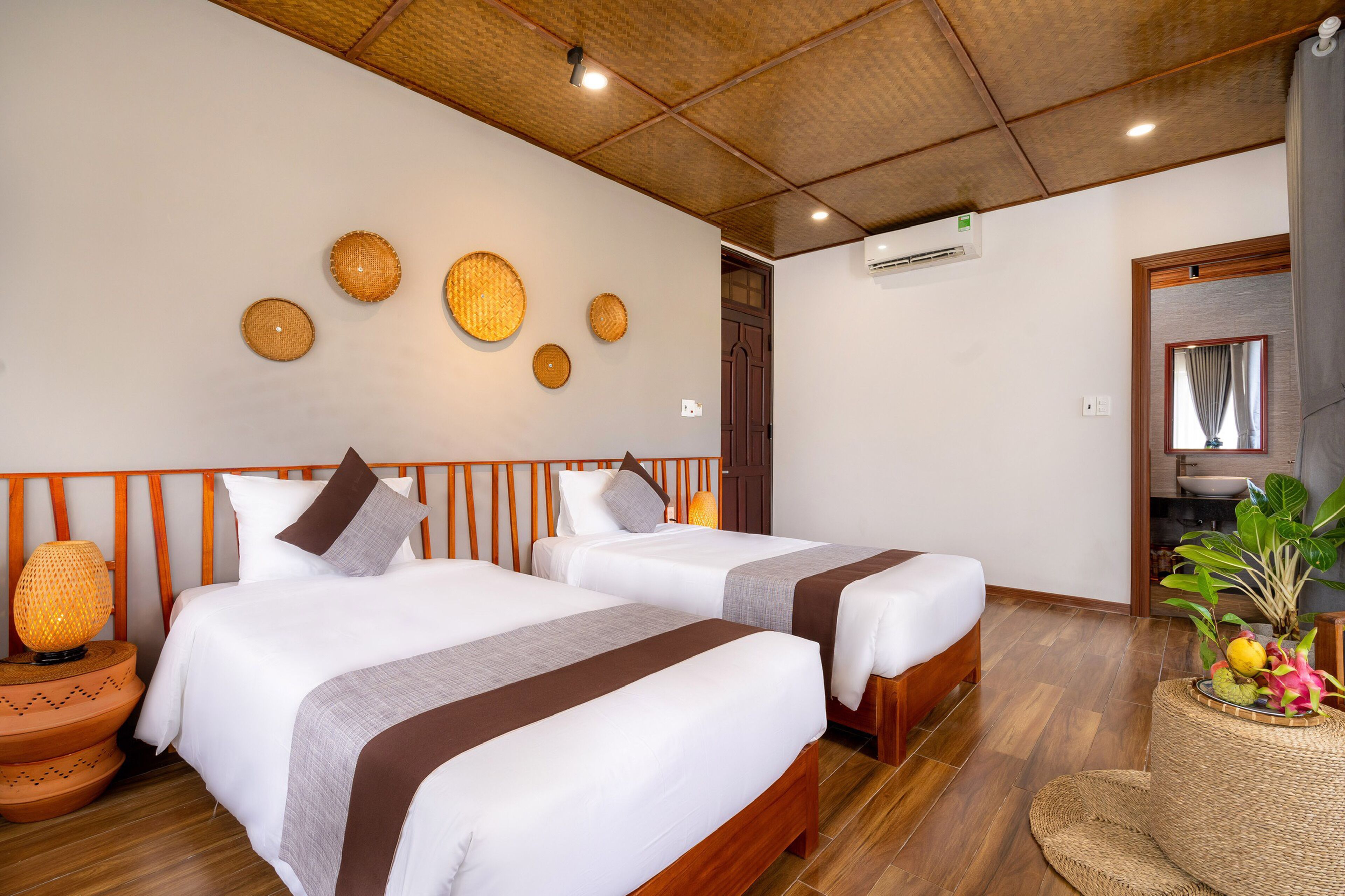 A hotel room with two beds, a wooden ceiling, and a wall-mounted air conditioner.
