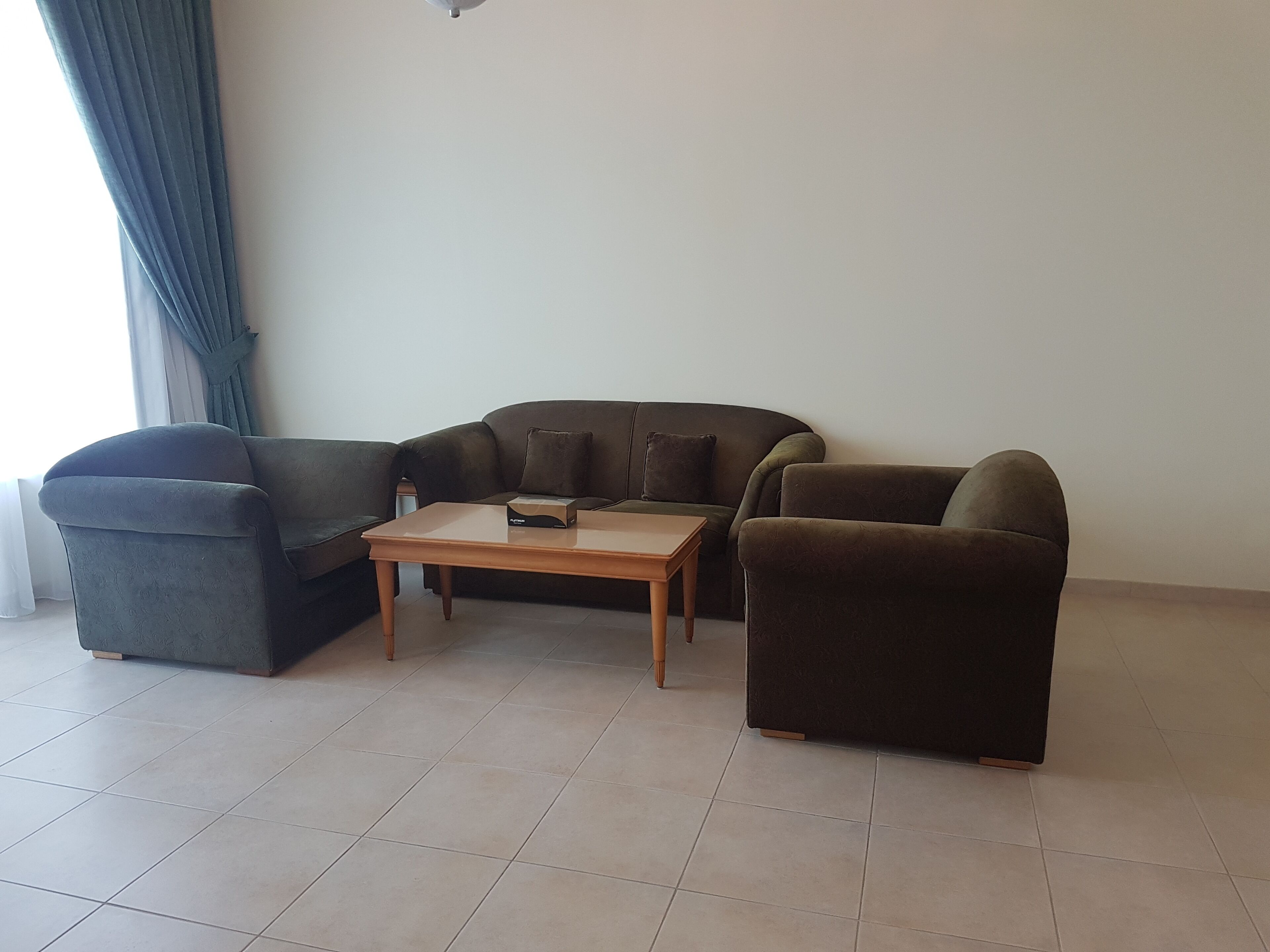 Un salon comprenant un canapé, une table basse et une fenêtre avec des rideaux.