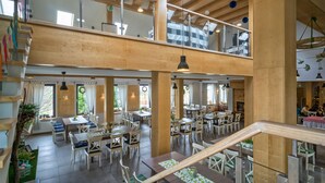 A spacious, multi-level restaurant with wooden beams, large windows, and a variety of seating arrangements. - Hotel Chojnik (Podgorzyn)
