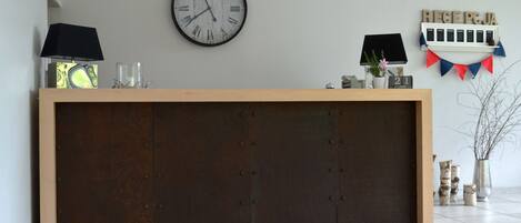 A reception desk with a clock, a lamp, and a sign that reads "RECEPCIA".