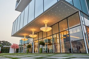 Un bâtiment moderne doté de grandes fenêtres en verre, d’un toit plat et de trois lustres suspendus.