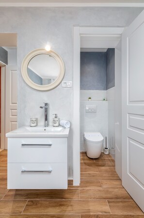 A modern bathroom with a white vanity, a round mirror, and a toilet. - Pool, grill, WiFi, bicycles, billiards, dishwasher, washing machine (Loborika)
