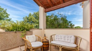 A balcony with wicker furniture, a wooden barrel, and a view of greenery. - Pool, grill, WiFi, bicycles, billiards, dishwasher, washing machine (Loborika)