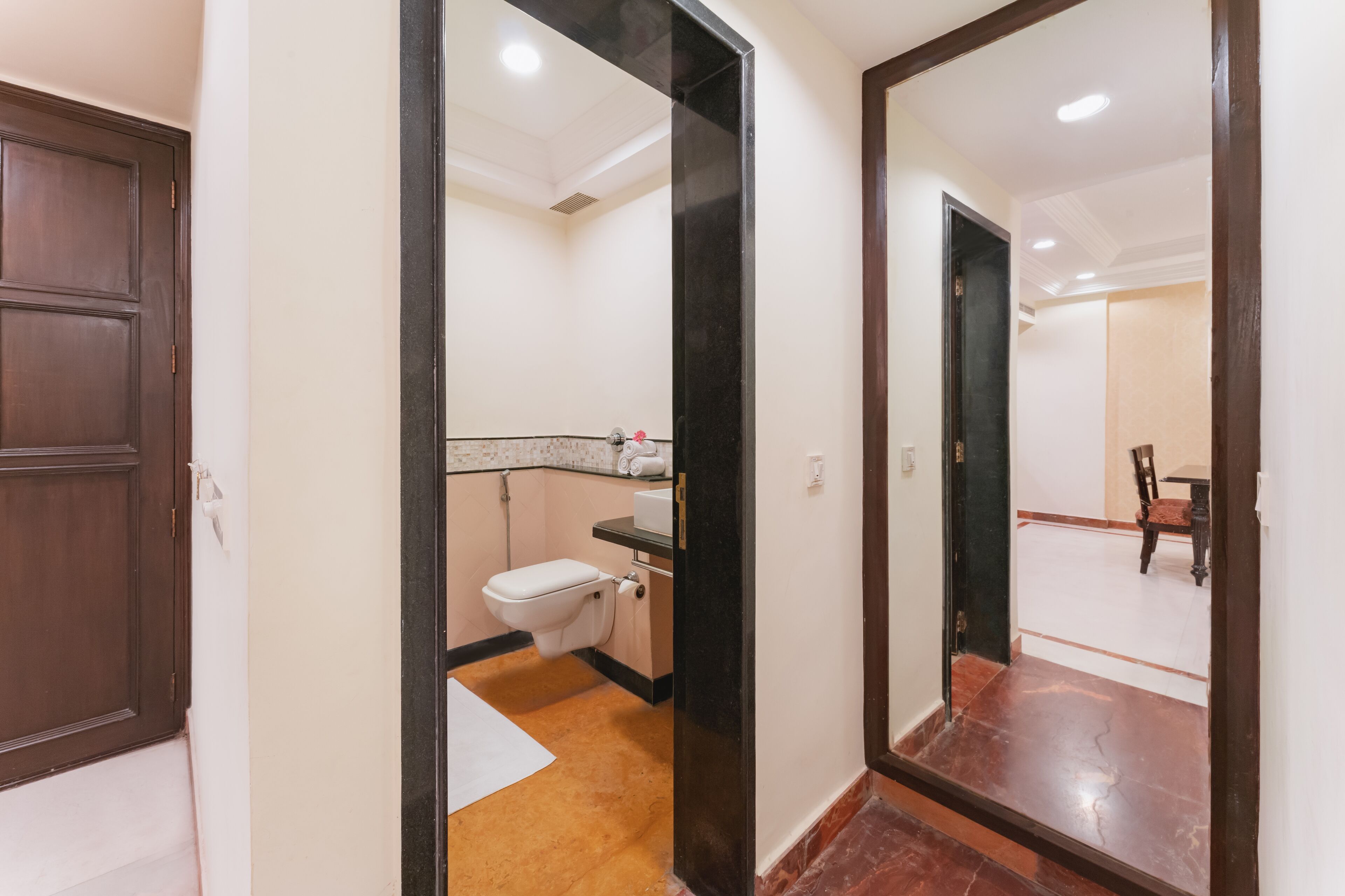 A hotel bathroom with a toilet, sink, and mirror.