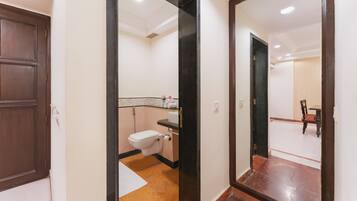 A hotel bathroom with a toilet, sink, and mirror.