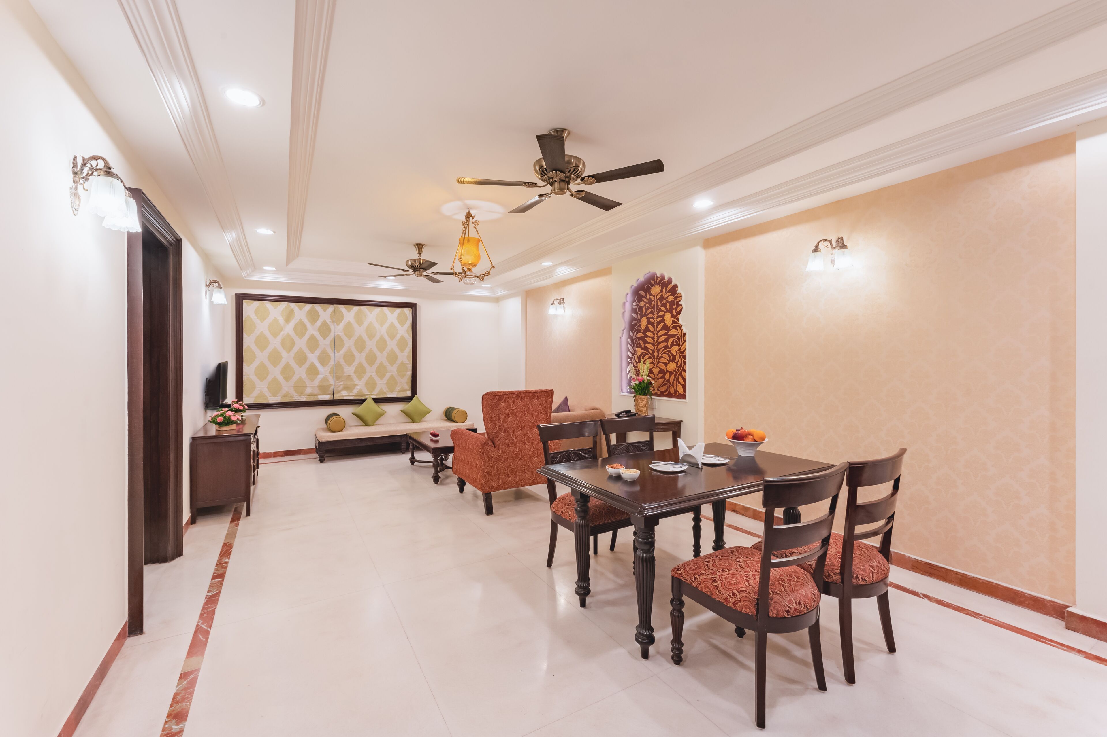 A dining area with a table and chairs, ceiling fans, and wall-mounted lights.