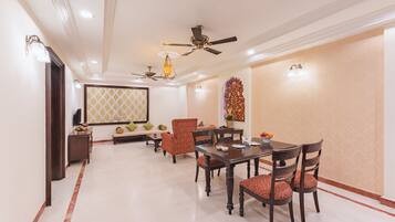 A dining area with a table and chairs, ceiling fans, and wall-mounted lights.