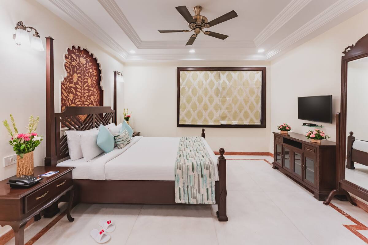 A bedroom with a bed, bedside table, nightstand, TV, and a ceiling fan.