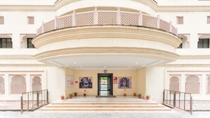 Een meerlaags gebouw met een gebogen entree, plantenbakken en decoratieve details.