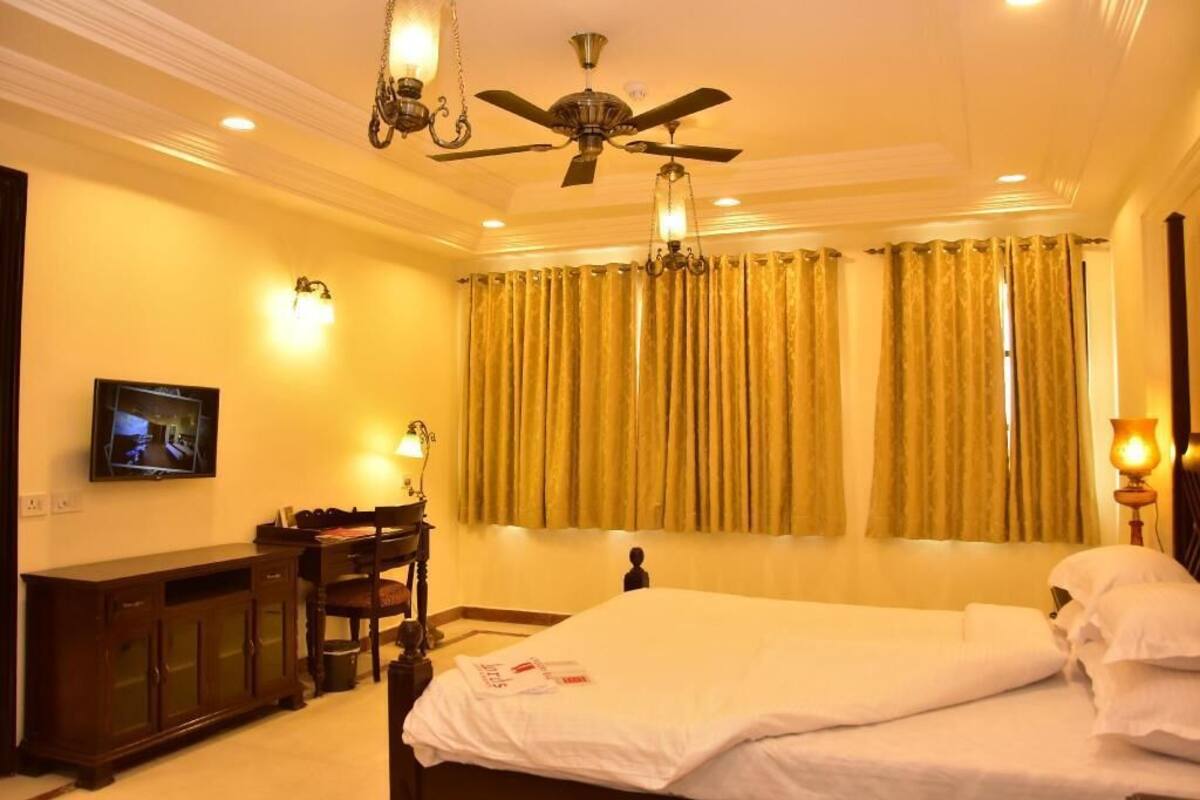 A hotel room with a bed, a desk, a chair, a television, and a ceiling fan.